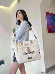 Detailed view of cream canvas tote bag featuring Summer Nice embroidery and adjustable strap