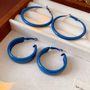 Klein blue geometric hoop earrings set in minimalist design on beige jewelry display