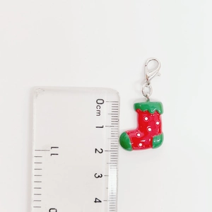 Detalle del colgante calcetín de Navidad rojo y verde con dimensiones en una regla