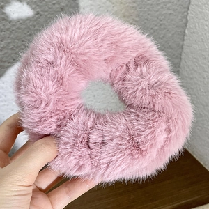 Close-up of a pink plush scrunchie held by hand showing soft fuzzy texture