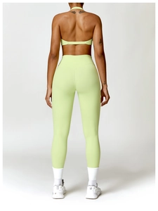 Détail du dos d'une brassière de yoga vert clair à brides croisées et legging taille haute