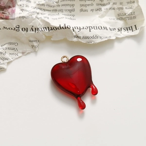 Detailed view of a red melting heart pendant with a gold ring for DIY jewelry making