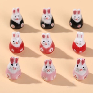Macro shot of 9-piece cute cartoon rabbit beads in black red and pink for DIY crafts
