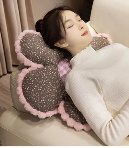 Detail of flower-shaped plush cushion with dark grey floral pattern and pink faux fur trim