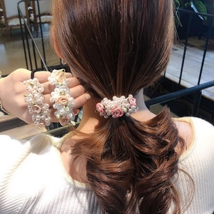 Elegant pearl and satin flower hair ties shown in pink and cream on a ponytail