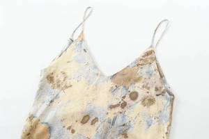 Détail du décolleté en V et des fines bretelles sur une robe longue satinée marbrée