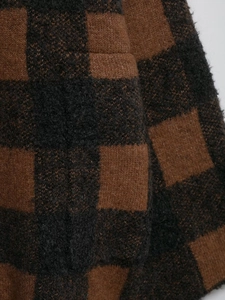 Close-up of thick knit plaid cardigan fabric with soft brown and black wool texture