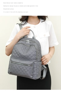 Detalle de mochila de nailon acolchado gris con cremalleras dobles de metal plateado