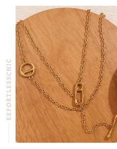 Detailed view of a gold pig nose pendant necklace with toggle clasp on a wooden tray