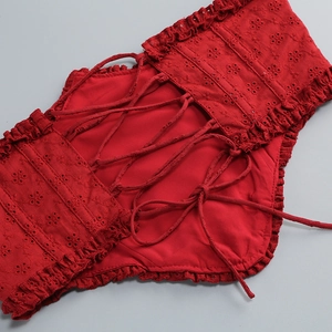 Detailed view of red corset lace-up closure with embroidery and ruffle trimming