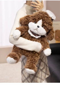 Detailed view of large plush dog toy with lace bib and white hat held by a model