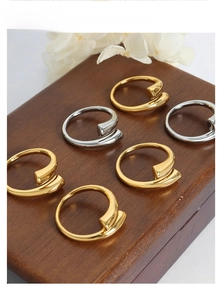 Polished gold and silver wrap rings arranged on a wooden jewelry box with dried flowers