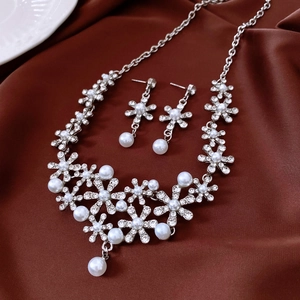 Detailed macro view of diamond flower necklace and pearl earrings on silk fabric