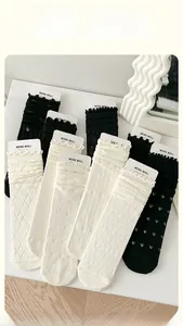 Détail de chaussettes en coton avec motifs cœurs, textures treillis et dentelle