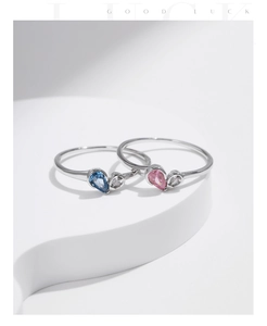 Macro detail of silver rings featuring pear-cut blue and pink stones on white steps