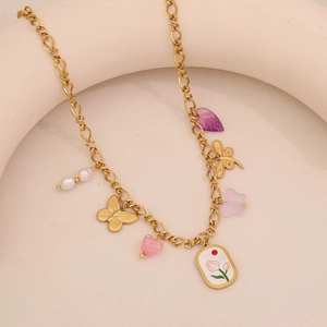 Dettaglio della collana dorata con ciondoli a farfalla, cuore rosa e tulipano