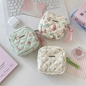 Detailed view of three quilted sanitary napkin storage bags with decorative zipper pullers
