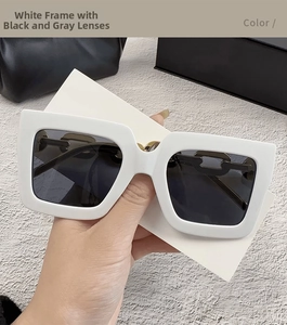 Detalle de gafas de sol cuadradas blancas de gran tamaño con patillas de cadena dorada