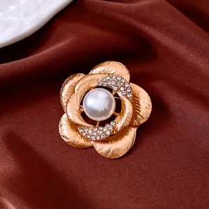 French luxury camellia flower brooch with pearl and crystals on dark red silk fabric