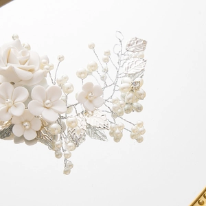 Silver bridal hair vine with white flowers and pearls on a clean reflective surface