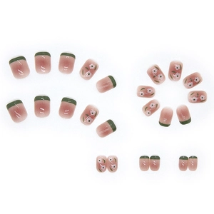 Short pink gradient press-on nails with dark green french tips and white flower patterns