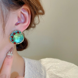 Gros plan de boucles d'oreilles rondes vintage avec pierre verte et cristaux colorés