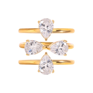 Detailed view of three stackable gold rings with pear-cut cubic zirconia in prong setting