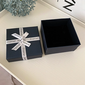 Detail of dark blue 7x9cm jewelry gift box with white ribbon and plush black interior