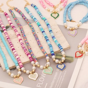 Detail of bohemian polymer clay necklaces with colorful beads and crystal heart pendants