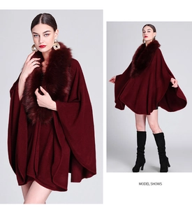 Detail of burgundy knitted cape with plush faux fur collar and elegant draped silhouette