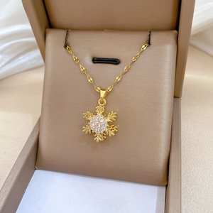 Detailed close-up of golden rotating snowflake pendant with sparkling crystals on water wave chain