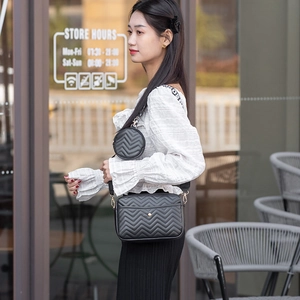 Detail of black V-quilted crossbody bag with a round coin purse and logo strap