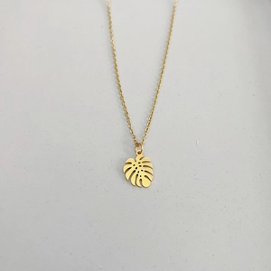 Detailed top view of a gold-plated monstera leaf pendant on a slim O-chain necklace
