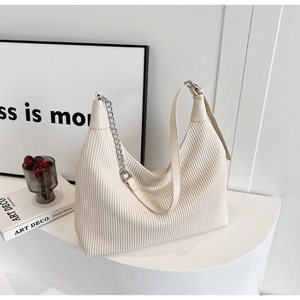 Détail du sac fourre-tout crème avec texture plissée verticale et chaîne argentée