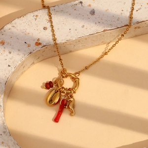 Close-up of 18K gold plated necklace with red enamel, shell and seahorse charms