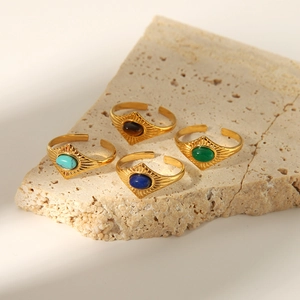 Detail view of four gold-plated adjustable rings with turquoise and lapis stones on stone