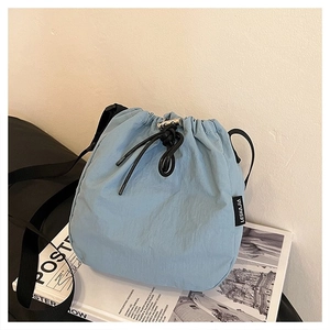 Detail of light blue nylon bucket bag with black drawstring and metal hardware adjustment