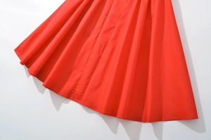 Gros plan de l'ourlet de la robe rouge vif avec des plis nets et un mouvement fluide