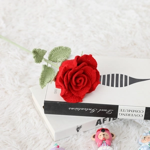 Detailed close-up of a handmade red crochet rose bouquet on a soft white plush background