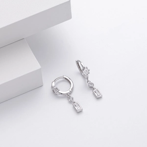 Detailed close-up of S925 silver hoop earrings with rectangular zircon on minimalist white cubes