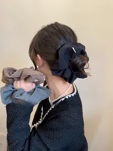 Close-up of oversized fabric hair scrunchies with polka dot texture in black and gray