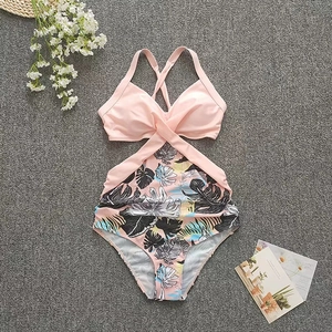 Detailed flat lay of pink cutout one-piece swimsuit with tropical leaf print and cross back