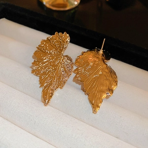 Macro shot of gold leaf earrings with intricate vein details and a vintage metallic finish