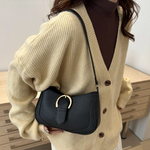 Detail of black lychee grain underarm bag featuring a vintage gold horseshoe buckle