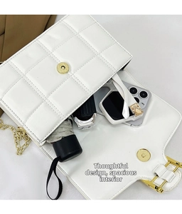Macro detail of white quilted handbag interior showing space for phone and umbrella