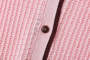 Close-up of pink knit fabric with dark brown trim and buttons for knitwear set
