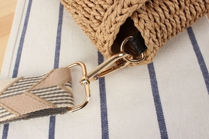 Close-up of handwoven straw bag with geometric strap and gold metal buckle detail