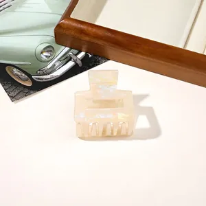 Detail of elegant cream rectangle hair claw clip with iridescent marbled texture finish