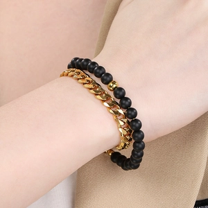 Close-up of men's gold Cuban chain and matte black onyx beaded bracelet set on wrist