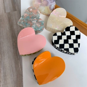 Set of colorful heart-shaped hair claws in pink, orange, and checkered marble patterns